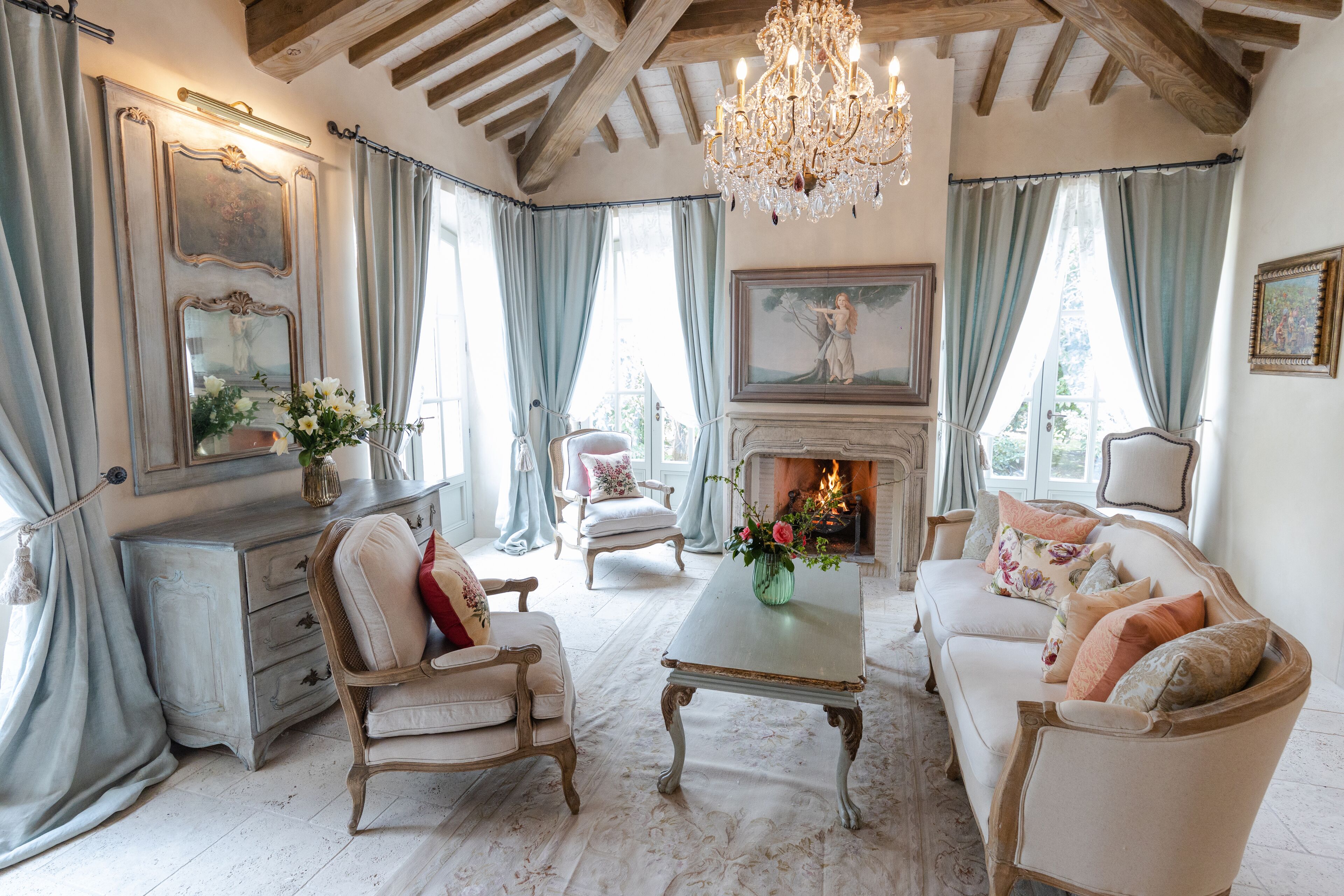 A traditional living room with a fireplace, wooden furniture, and a chandelier.