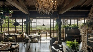 A rustic interior with a chandelier, wooden furniture, and large windows offering a view of the outdoors. - Borgo Santo Pietro (Chiusdino)