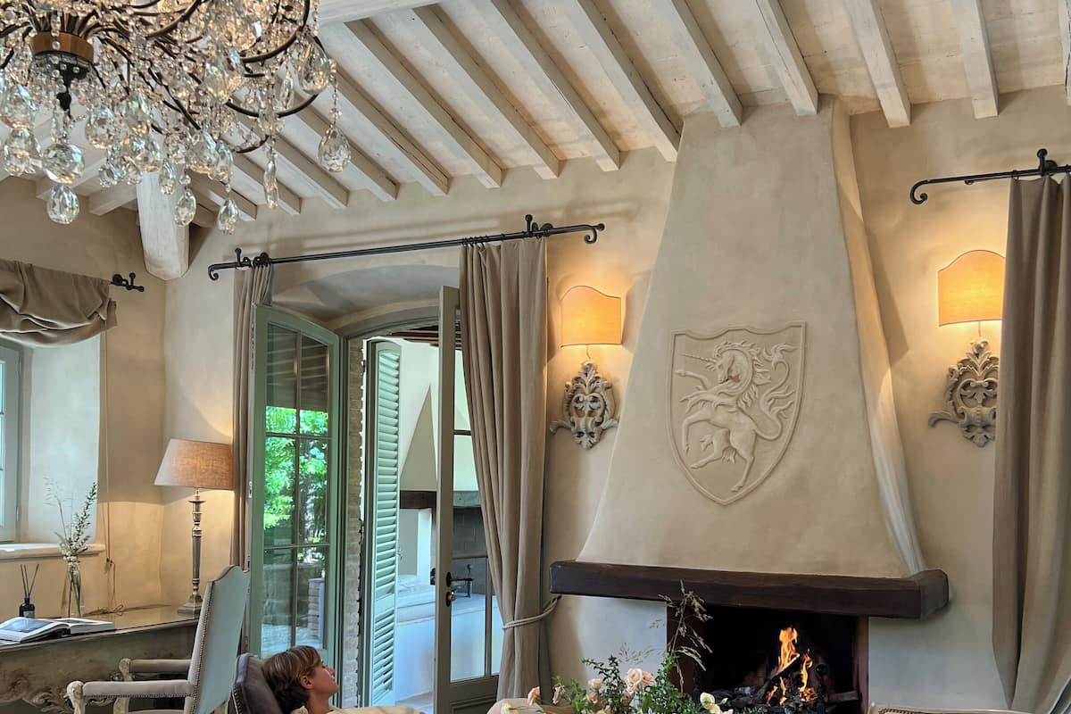 A cozy living room with a fireplace, elegant furniture, and a chandelier.