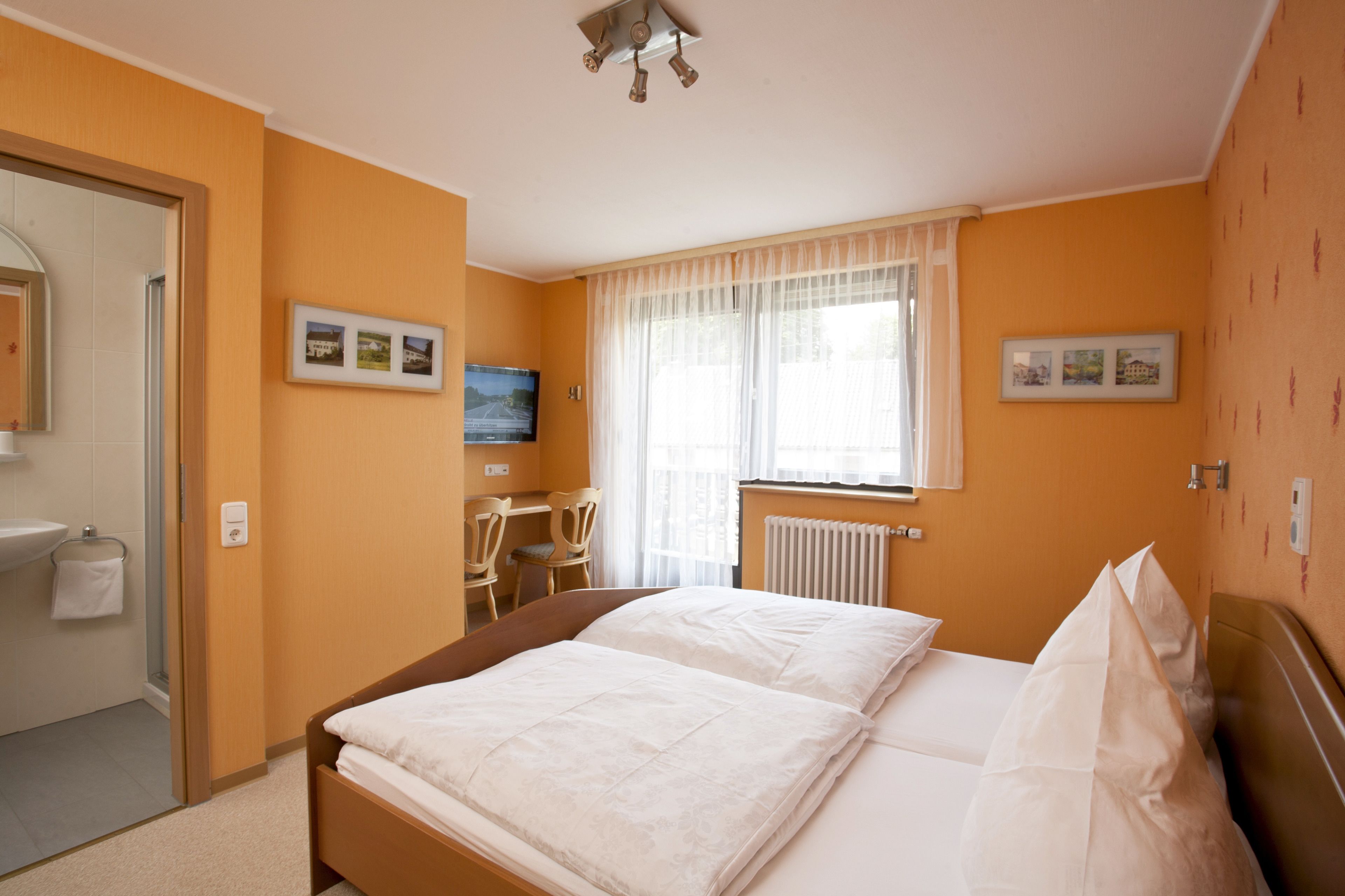 Una habitación de hotel con cama, escritorio y ventana con cortinas.