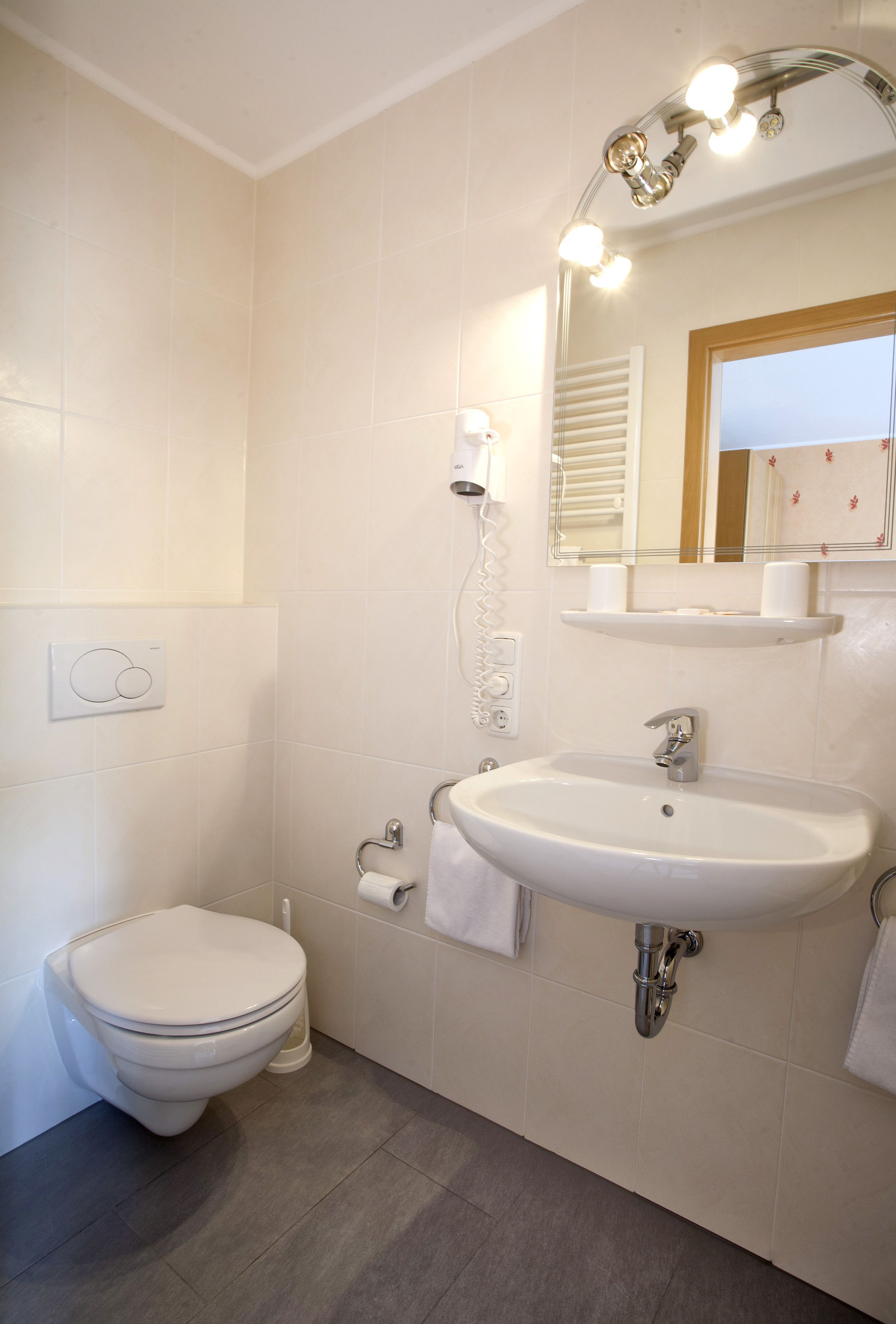 A bathroom with a toilet, sink, and mirror.