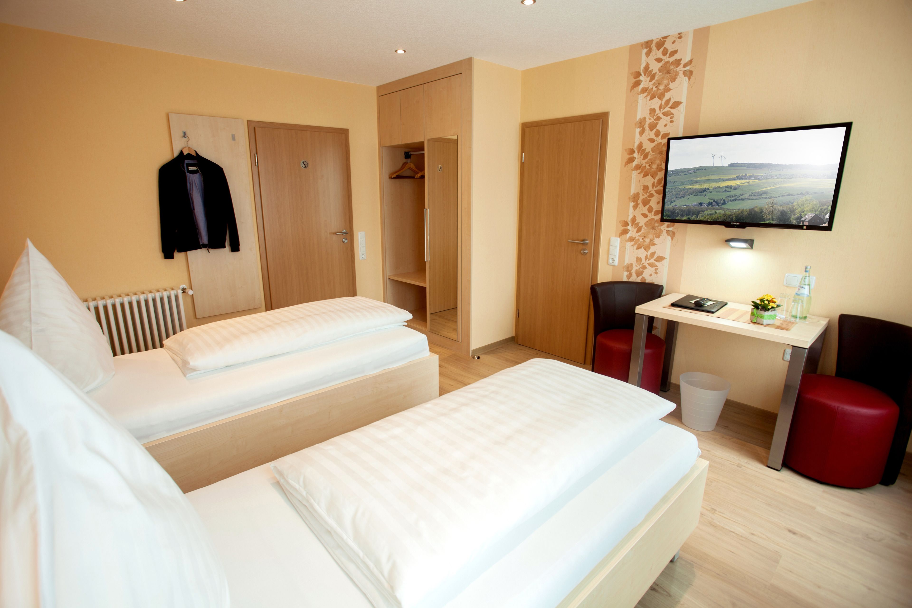 Une chambre d’hôtel avec deux lits, un bureau, une télévision et une armoire.