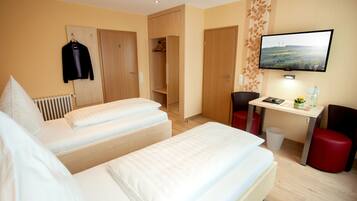 Een hotelkamer met twee bedden, een bureau, een televisie en een kledingkast.