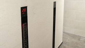 A reception area with a digital display showing the number 20, a wooden panel, and a vase with flowers on a table.