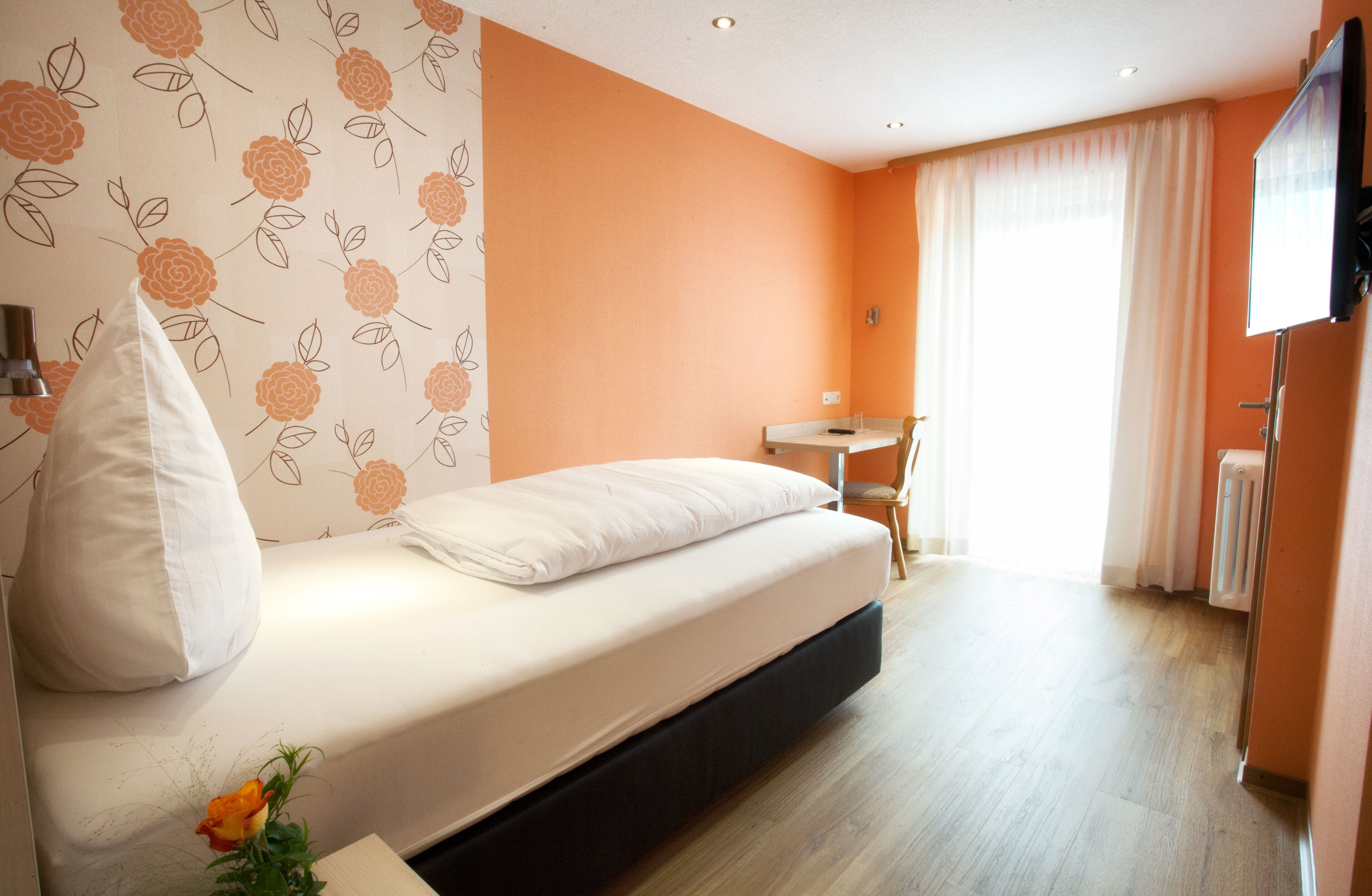 A bedroom with a bed, a desk, and a radiator.