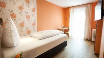 A bedroom with a bed, a desk, and a radiator.