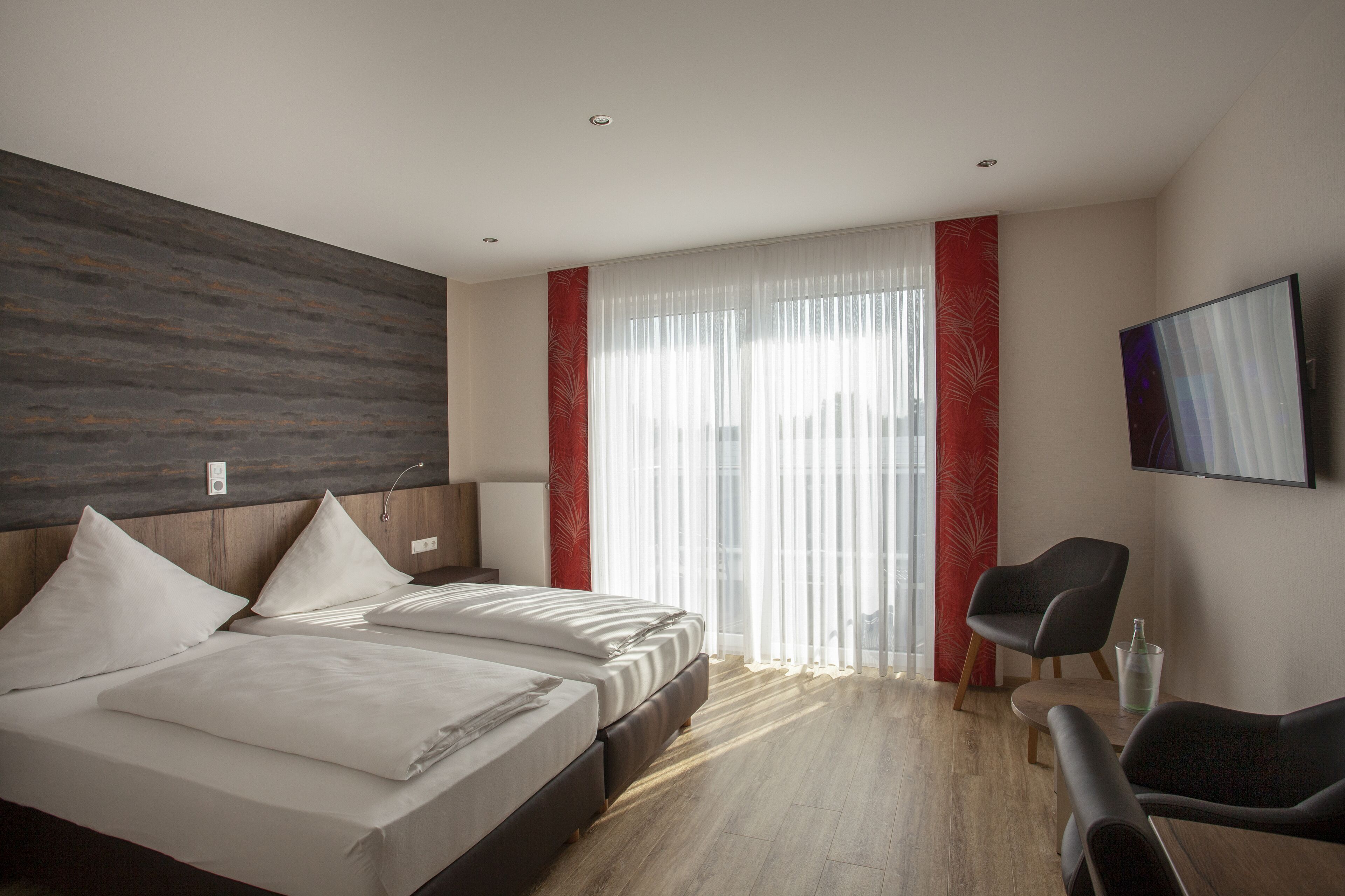Una habitación de hotel moderna con una cama grande, un escritorio y un televisor montado en la pared.
