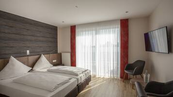 Una habitación de hotel moderna con una cama grande, un escritorio y un televisor montado en la pared.