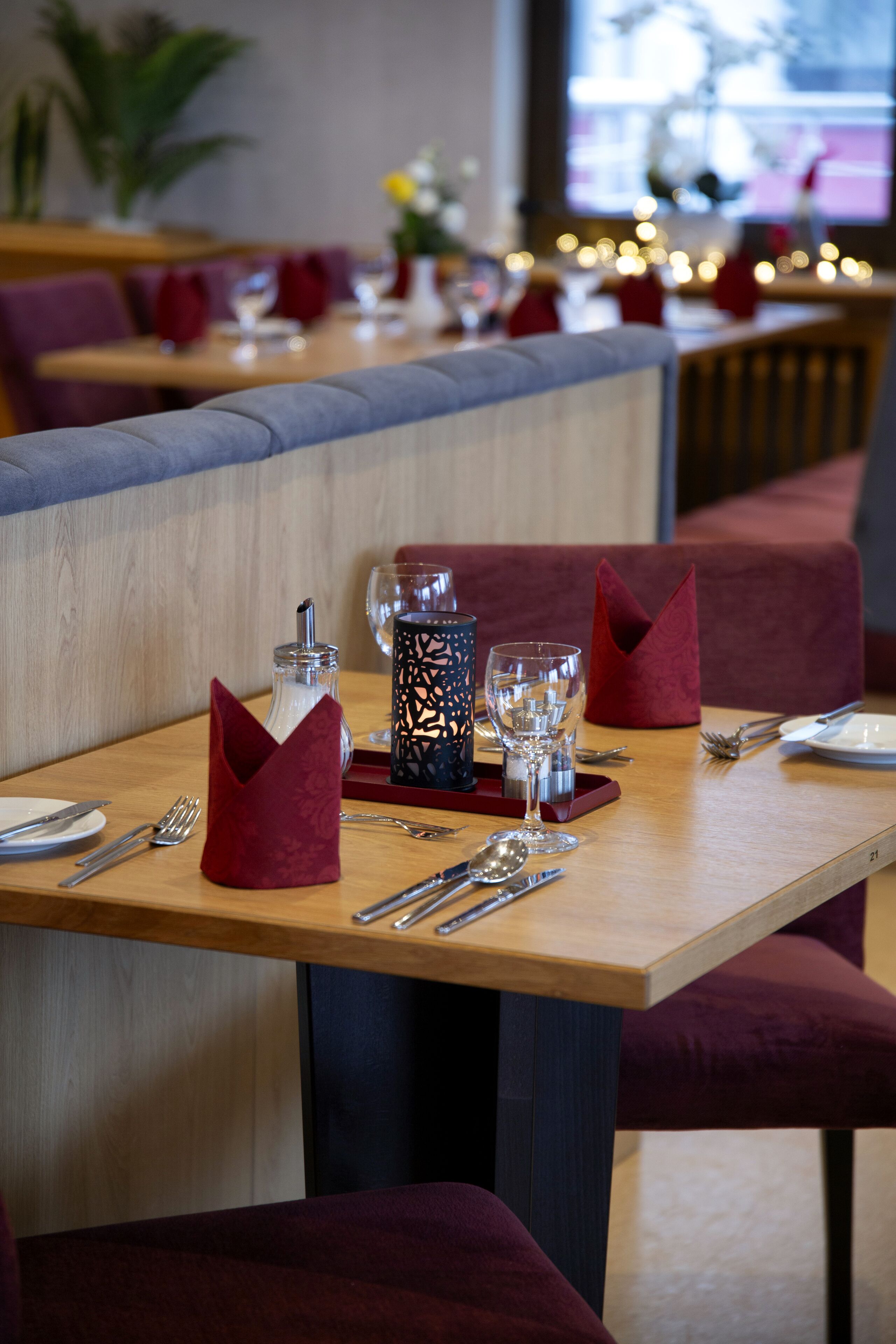 Un ambiente de restaurante con una mesa de madera preparada para dos comensales, incluyendo cubiertos, vasos y un candelabro.