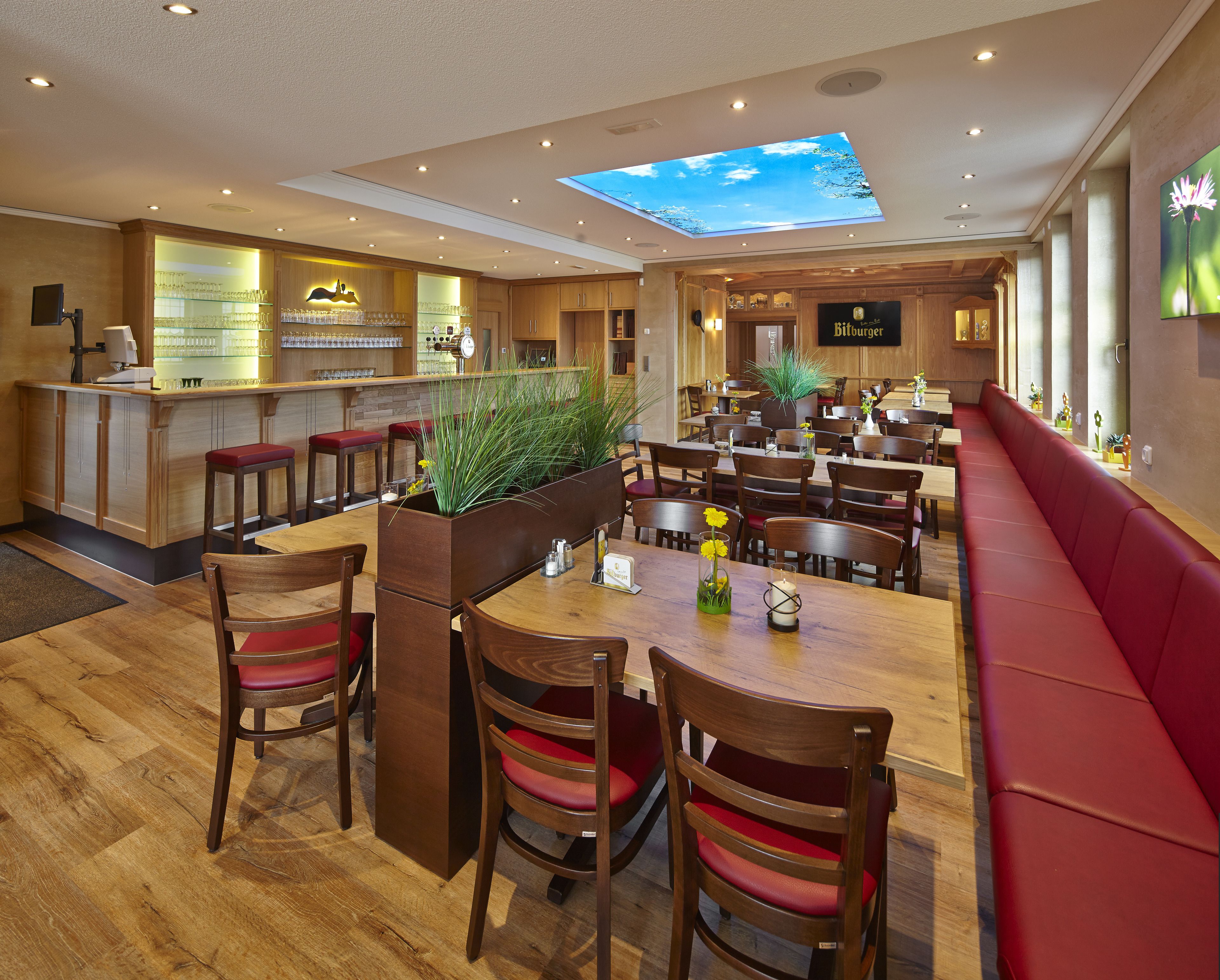 Un restaurante con zona de bar, muebles de madera y tragaluces.