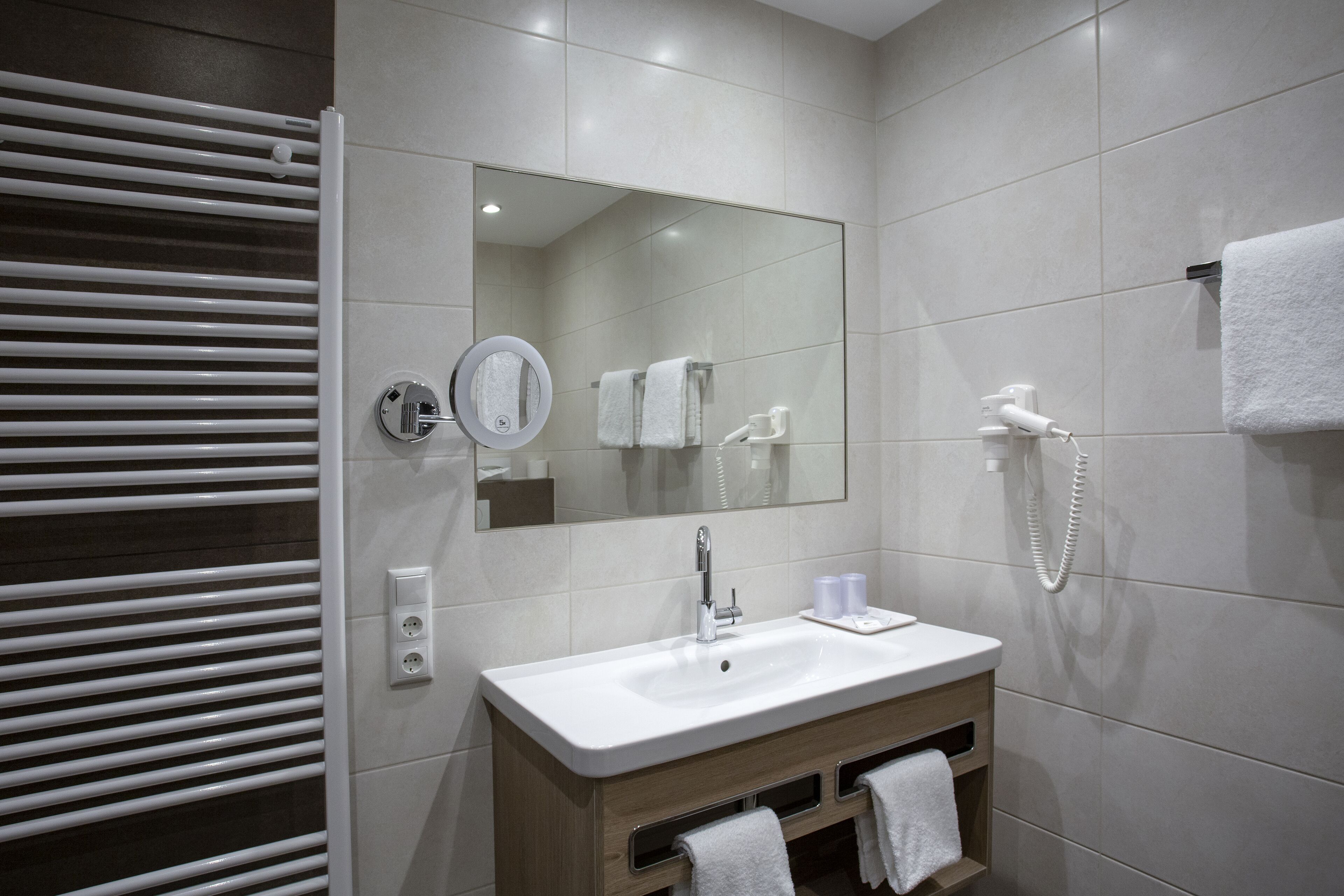 A modern bathroom with a white sink, mirror, and towel rack.