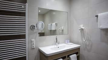 A modern bathroom with a white sink, mirror, and towel rack.