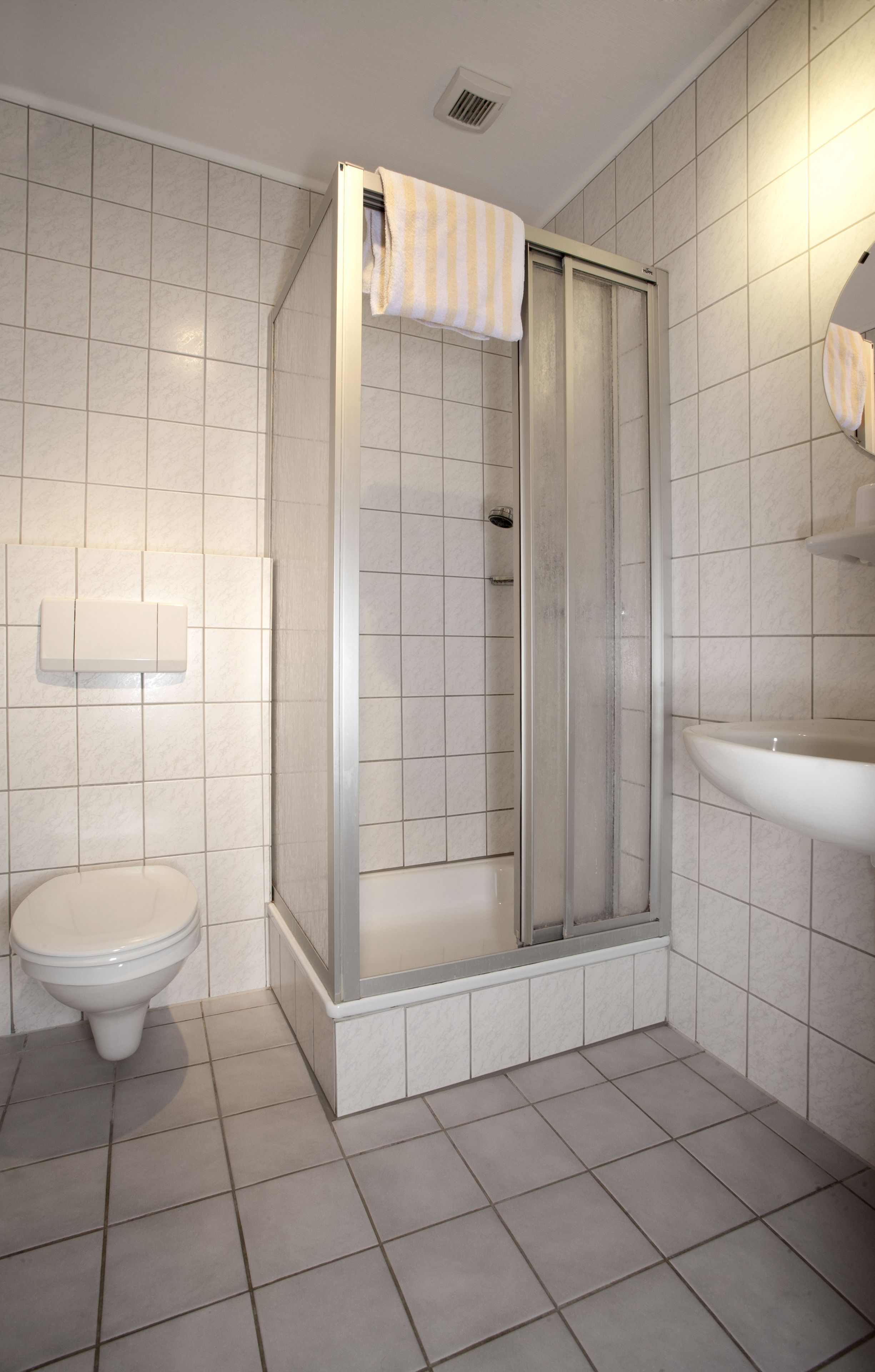 A bathroom with a toilet, a shower enclosure, and a sink.