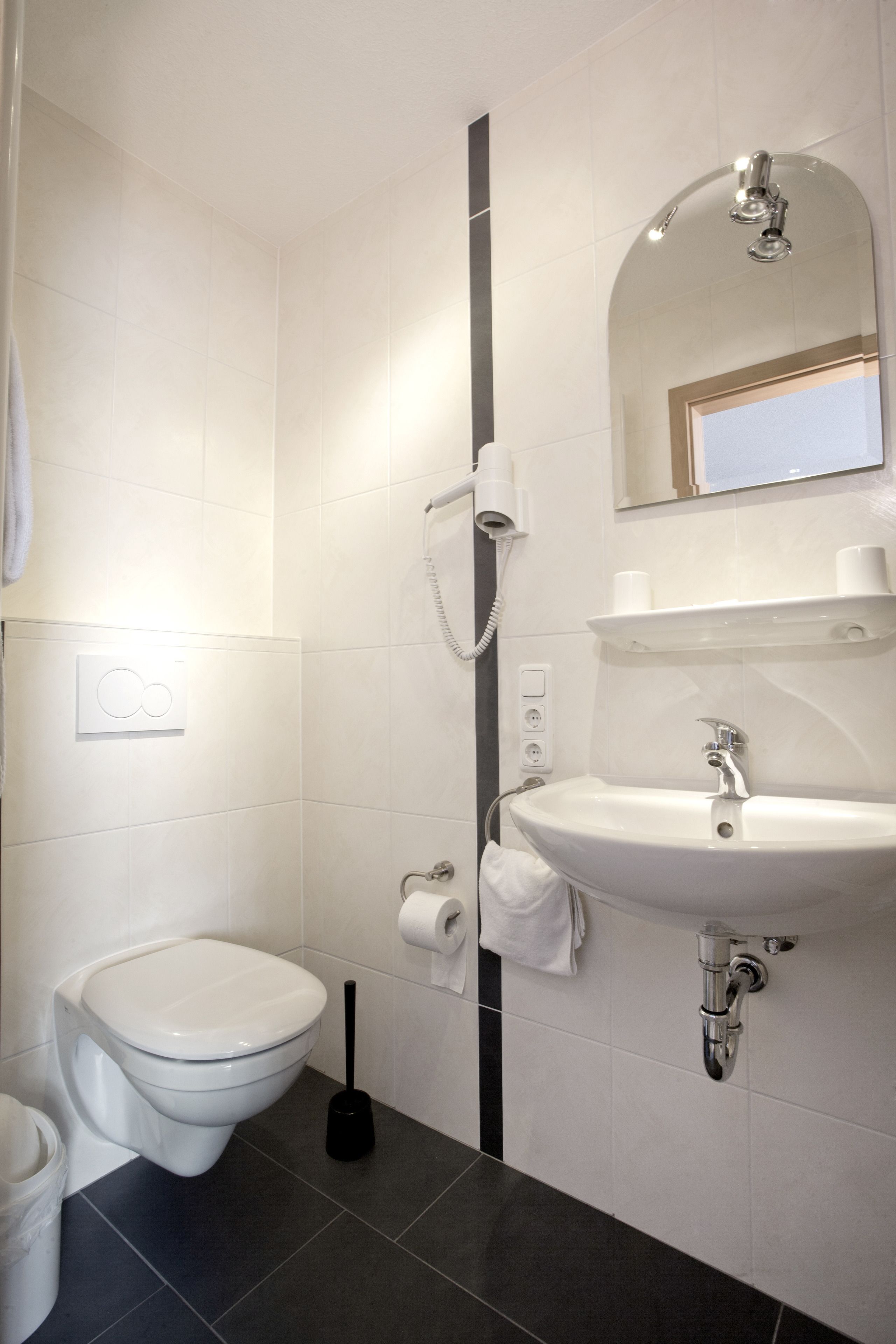 A modern bathroom with a toilet, sink, and shower.