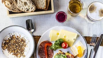 A breakfast setting with bread, fruit, cheese, and a plate with eggs and vegetables.