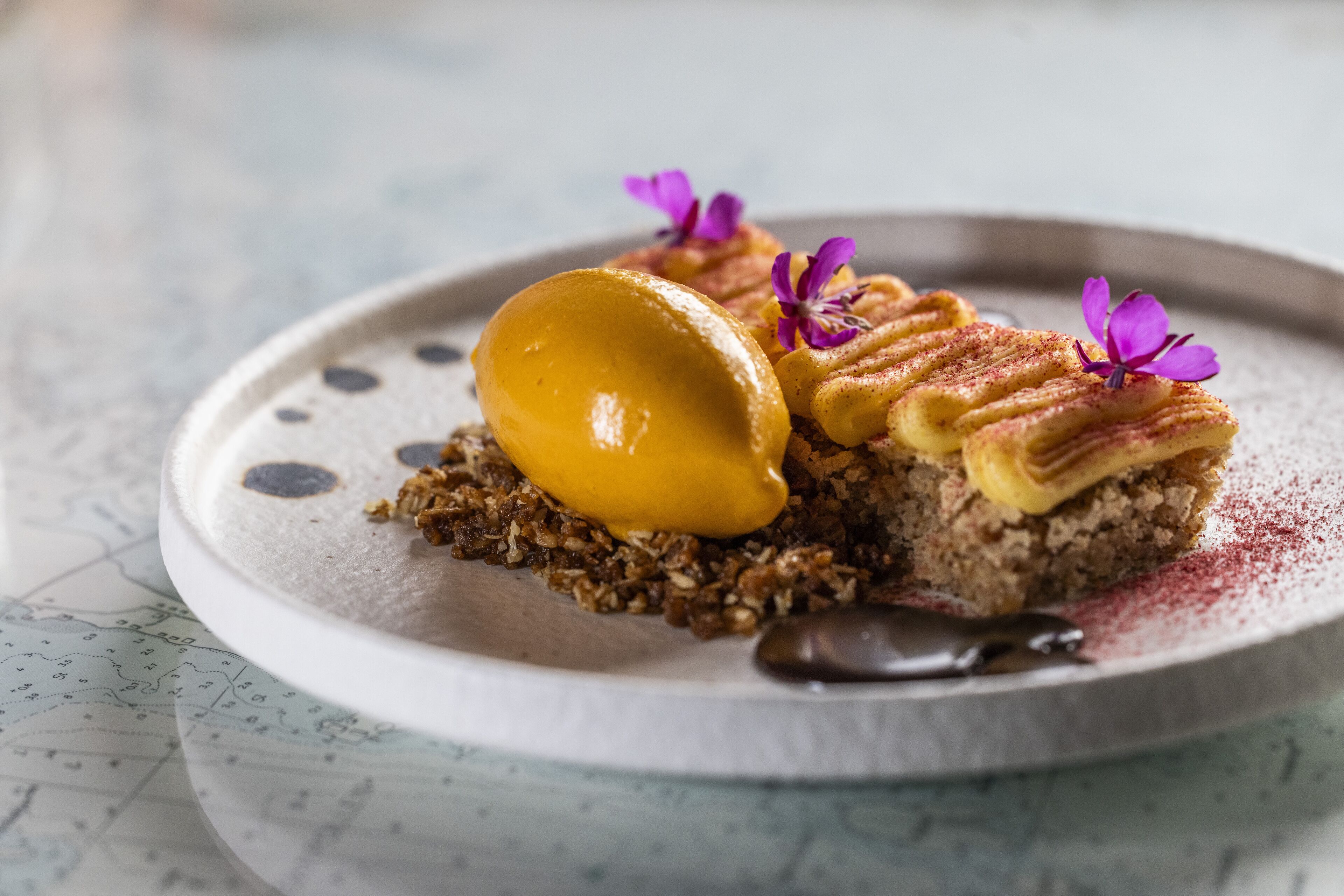 A dessert plate with a scoop of ice cream, a piece of cake, and a chocolate sauce.