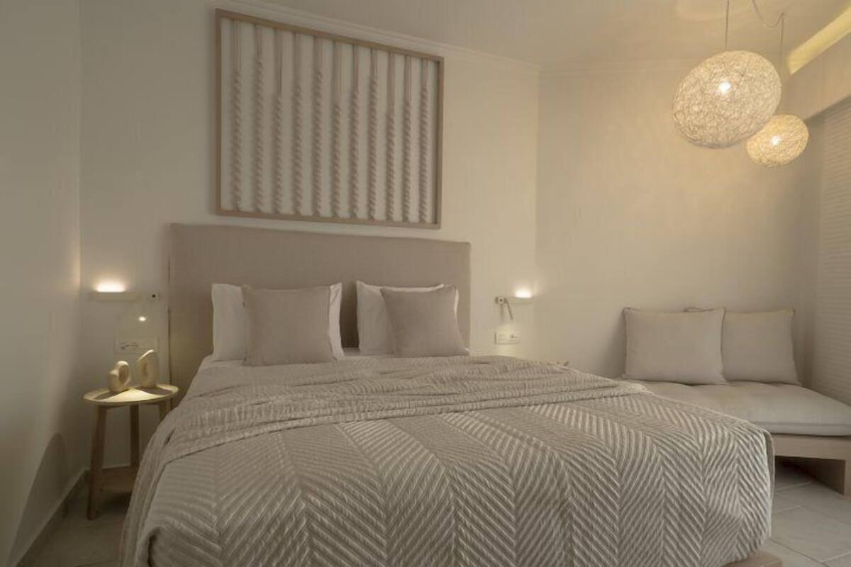 Un dormitorio moderno con una cama grande, una mesita de noche, una lámpara de pared y un candelabro colgante.