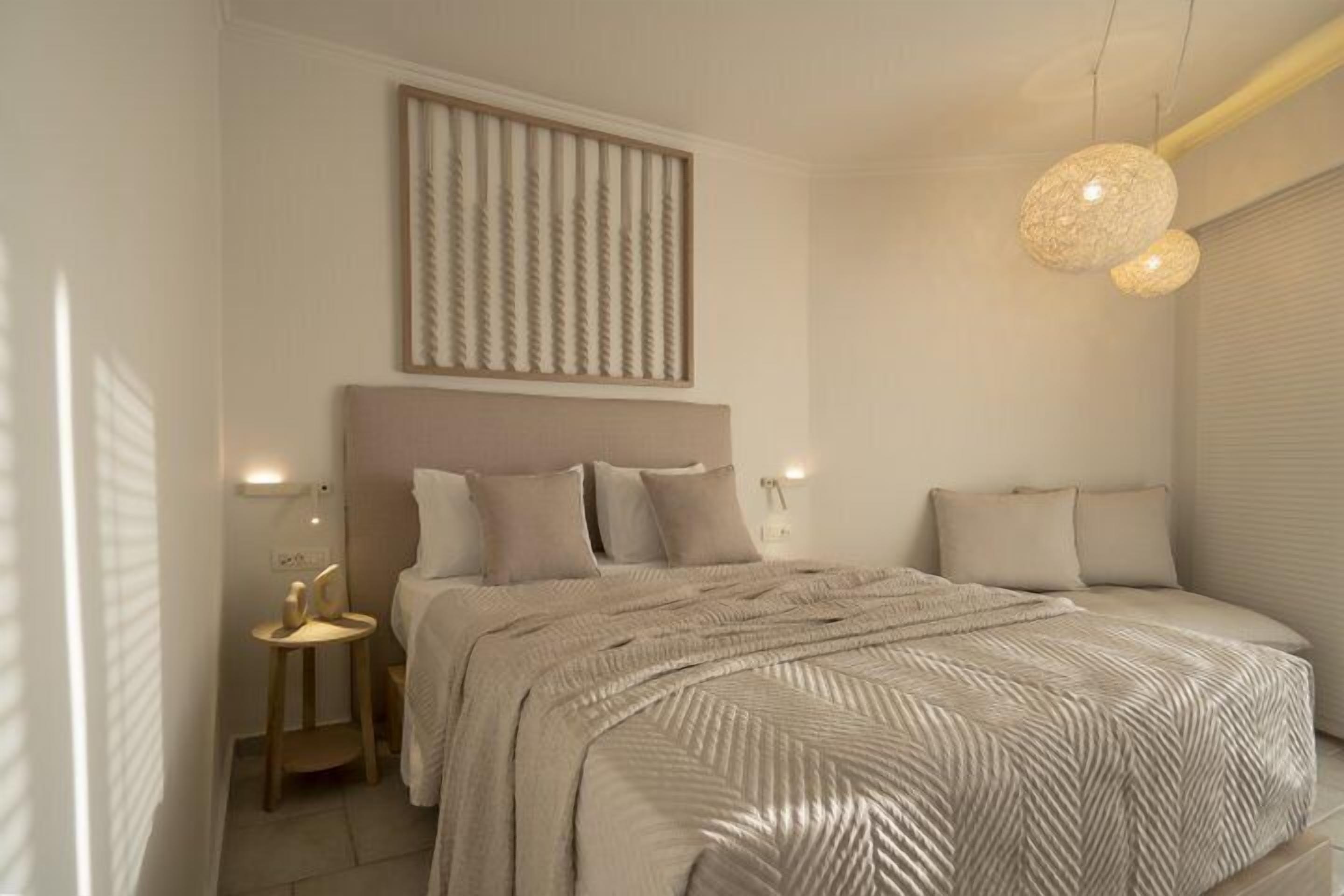 Ein modernes Schlafzimmer mit einem großen Bett, einem Kopfteil, Nachttischlampen und einer Wandleuchte.