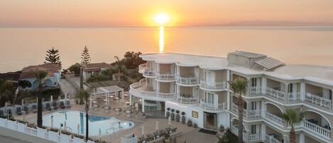 A resort with a pool, multiple balconies, and a sunset view.