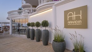 The exterior of Arkadia Hotel & Apartments with a modern design, featuring large potted plants and a clear view of the interior bar area. - Arkadia Luxury Hotel Apartments (Zakynthos)
