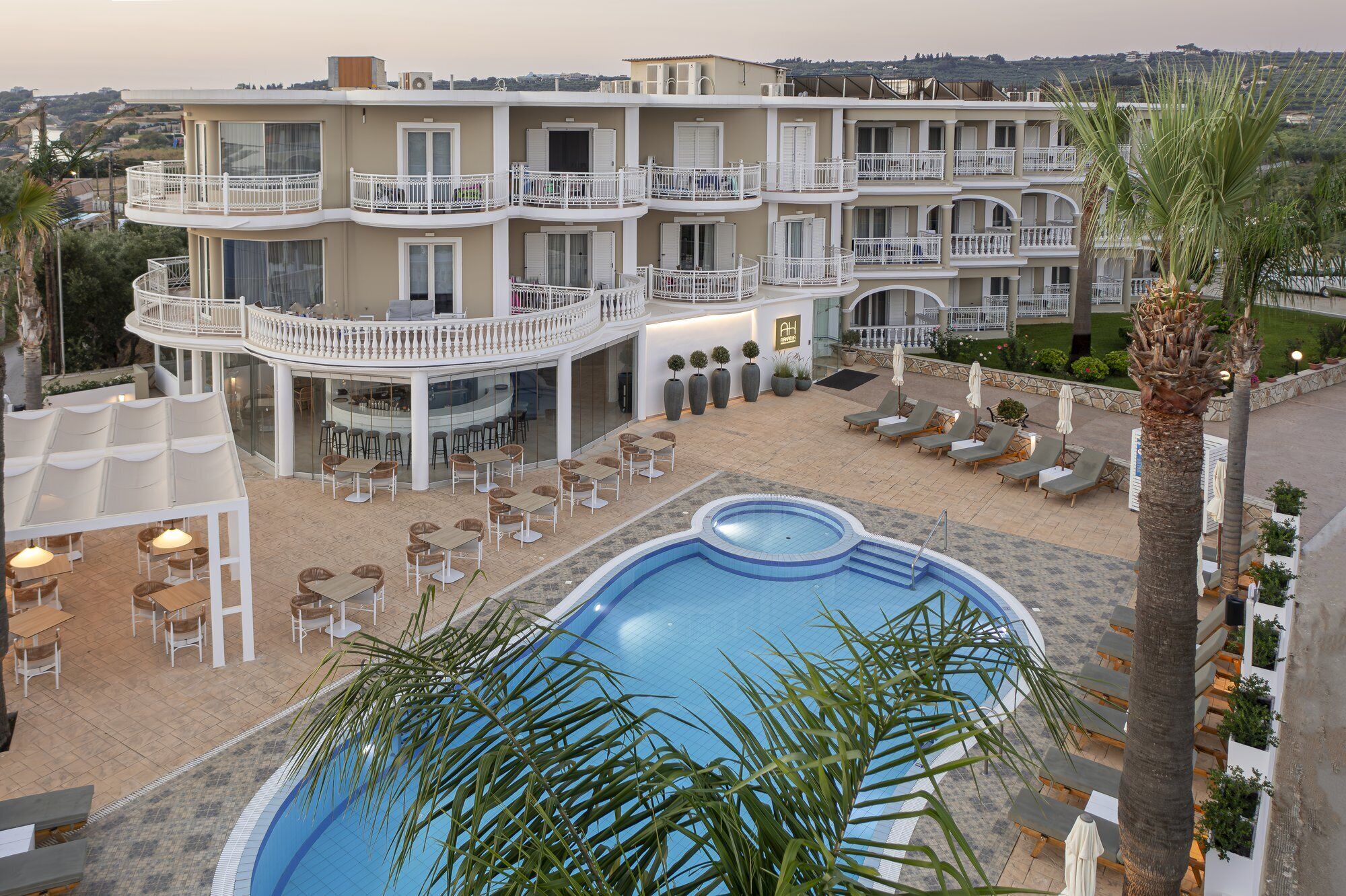 A hotel with a pool, outdoor seating, and a view of the surrounding landscape.