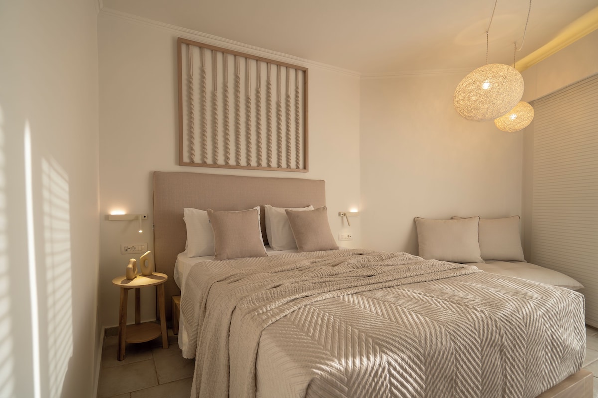 Une chambre à coucher avec un grand lit, une tête de lit, des tables de chevet et un luminaire fixé au mur.