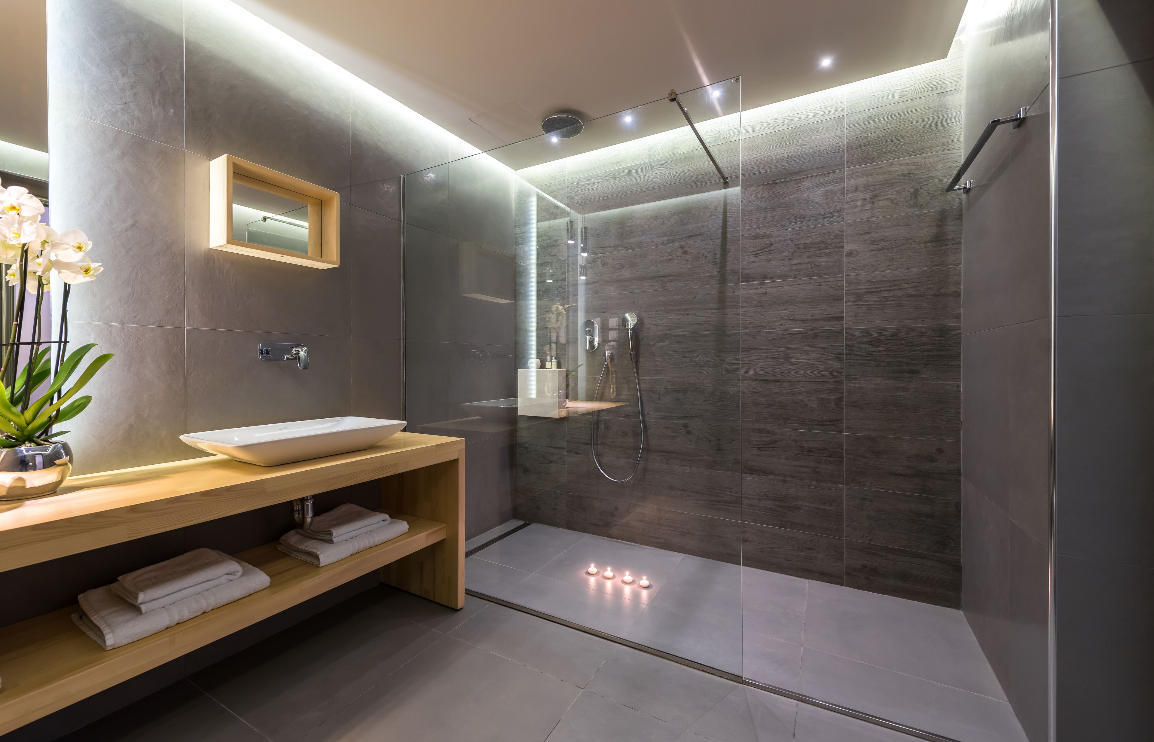 Une salle de bain moderne avec une douche  à parois de verre, un meuble-lavabo en bois et un miroir.