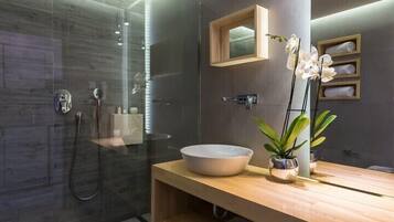 A modern bathroom with a glass shower enclosure, a wooden vanity with a large basin, and a mirror above it.