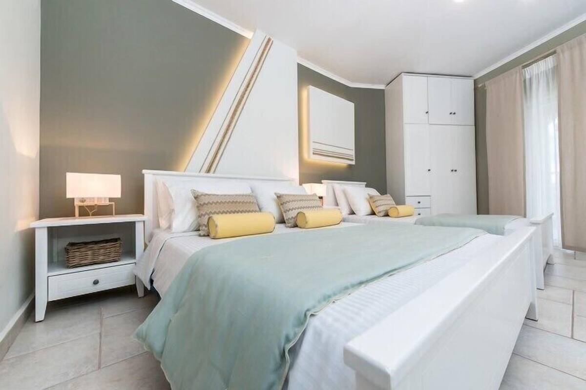 Un dormitorio moderno con una cama grande, mesitas de noche, un armario y un equipo de aire acondicionado instalado en la pared.