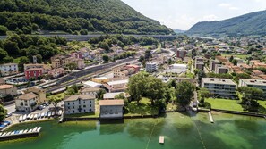 A riverside town with a mix of residential and commercial buildings, a bridge in the background, and a marina with boats.