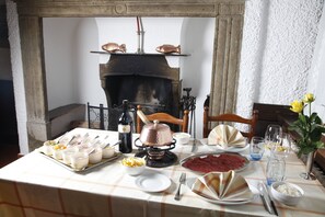 A dining table set with various dishes, a wine bottle, and a fireplace in the background. - Albergo Svizzero (Mendrisio)