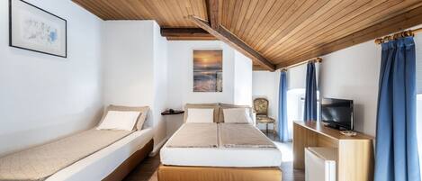 Una habitación con cama, escritorio, televisor y silla.