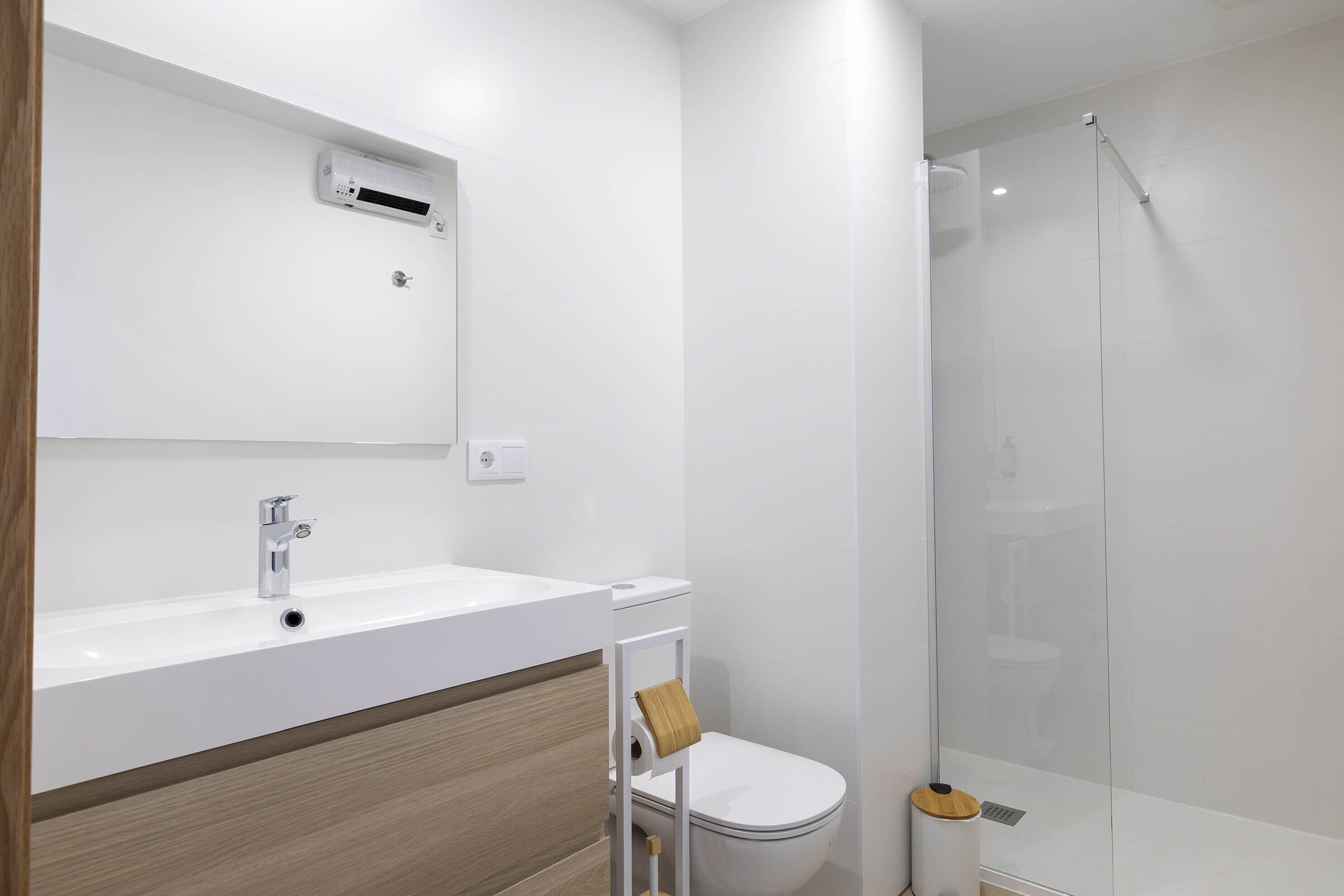 A modern bathroom with a white sink, a toilet, and a glass-enclosed shower.
