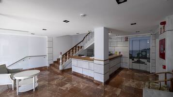 Cocina moderna con piso de mármol, escalera de madera y vista de la ciudad a través de un ventanal.