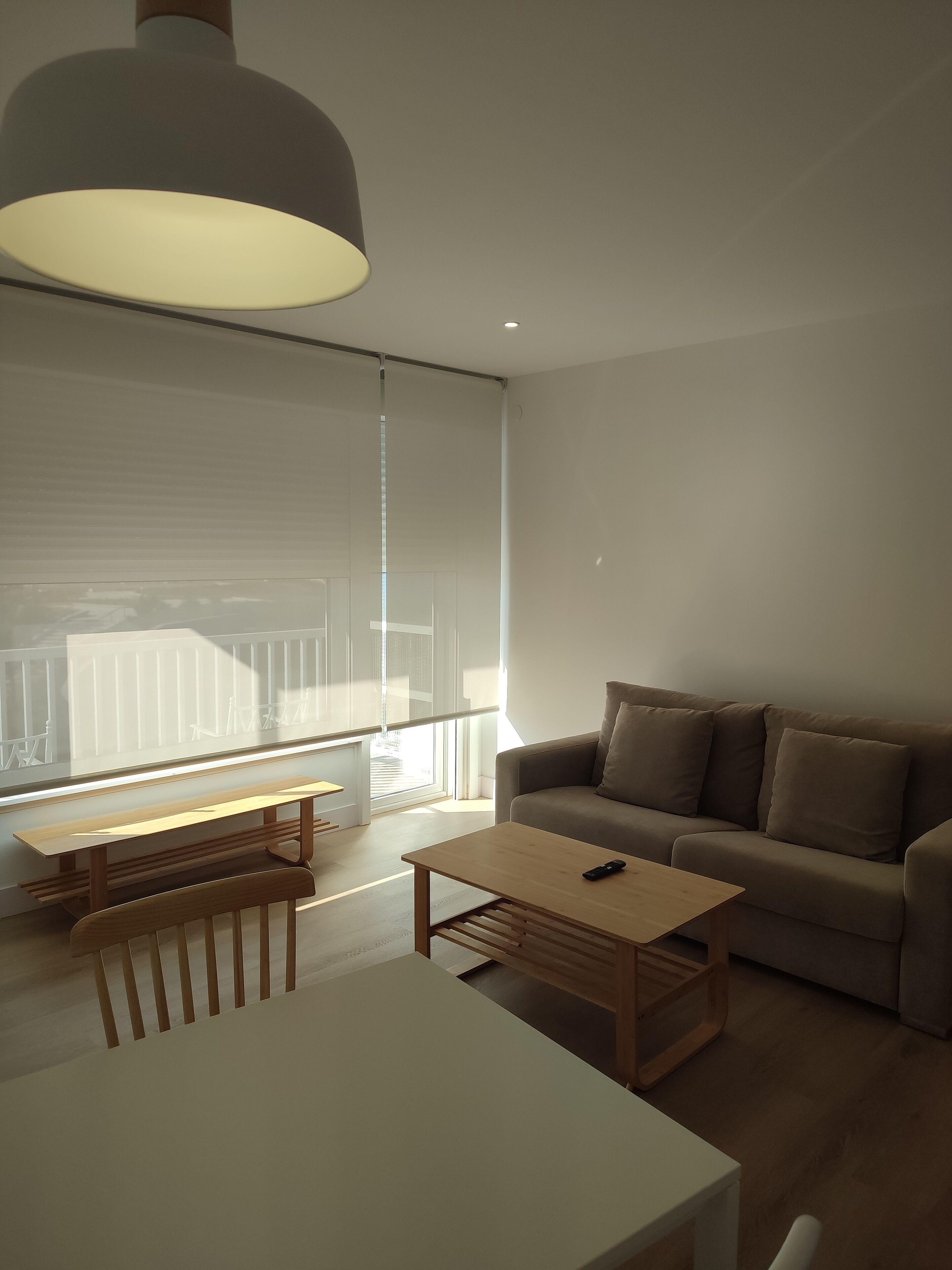 A modern living room with a sofa, a wooden coffee table, and a dining table.