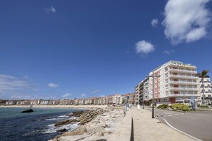 Hotel à beira-mar com fachada de pedra, varandas e vista para o mar.