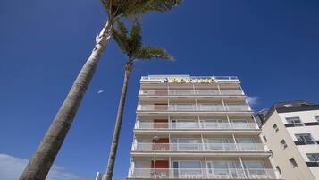 A multi-story building with balconies and a clear blue sky.