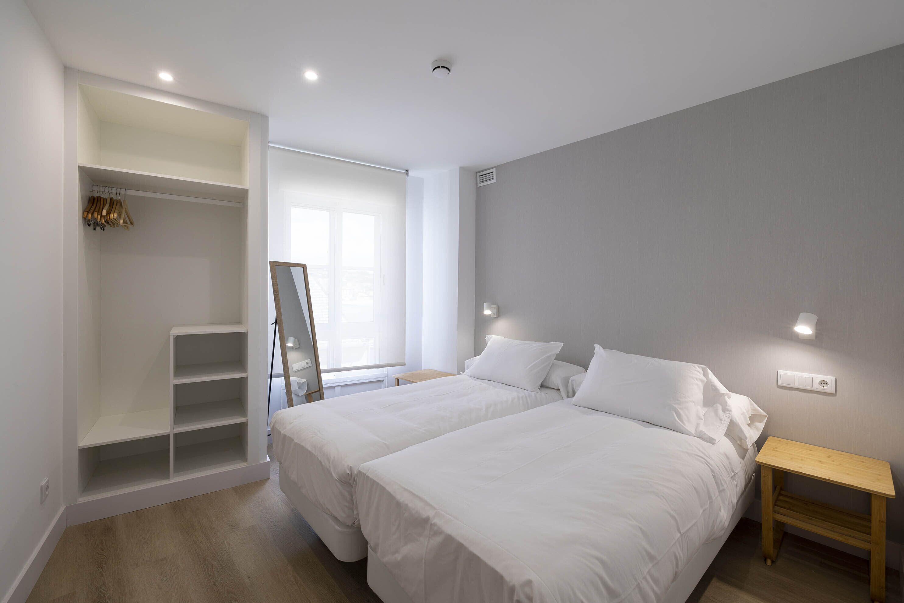 Une chambre avec deux lits, une armoire et une table de chevet.