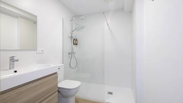 Een moderne badkamer met een wit wastafelmeubel, spiegel en toilet, en een douchecabine met glazen wanden.