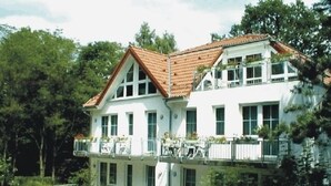 A two-story building with a white facade and a red-tiled roof. There are multiple windows and balconies with railings. - Waldhaus Mühlenbeck (Mühlenbecker Land)