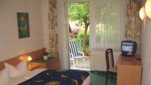 A hotel room with a bed, a desk, a chair, a television, and a view of the outdoors. - Waldhaus Mühlenbeck (Mühlenbecker Land)