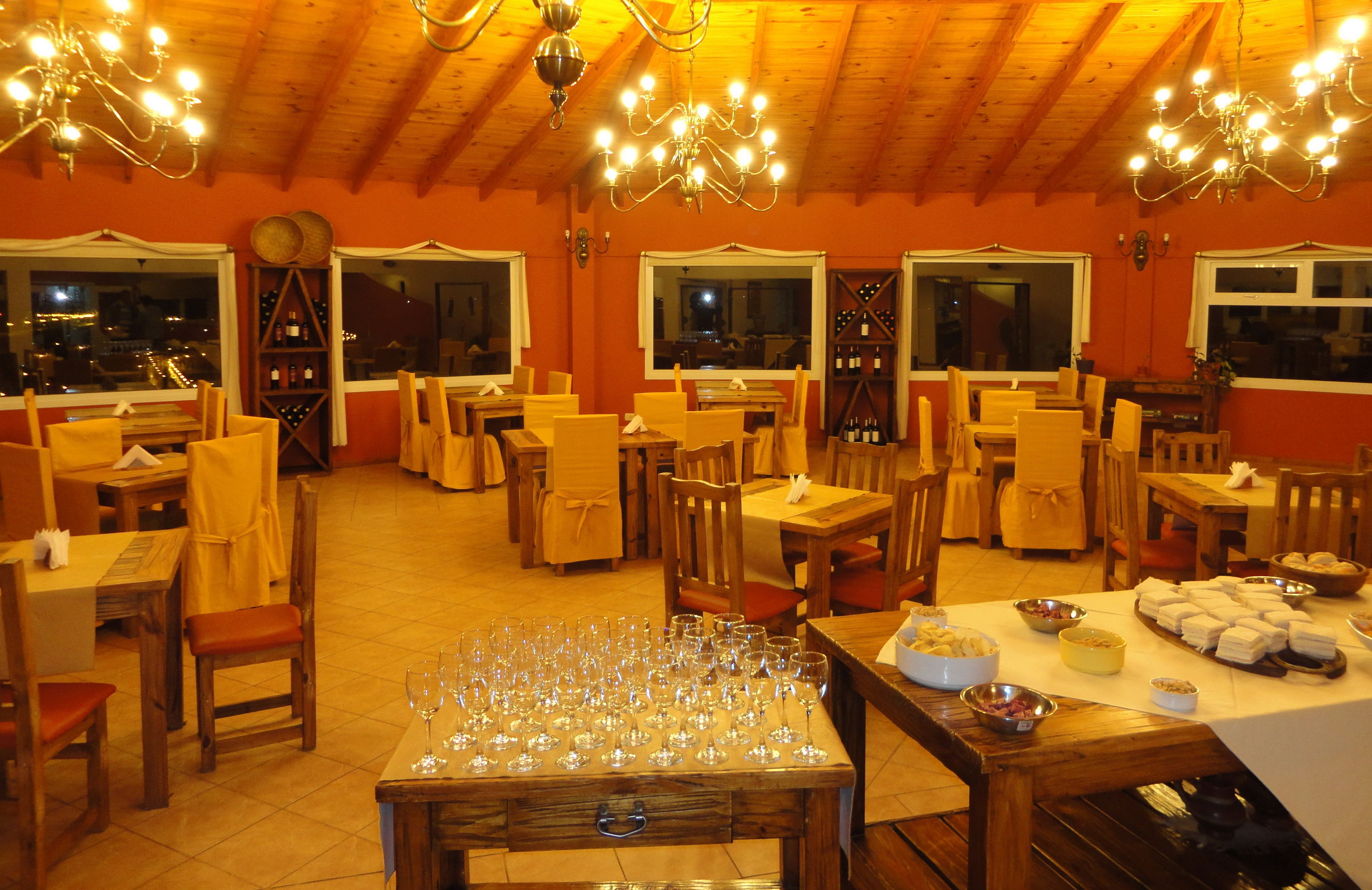 Un restaurant avec de nombreuses tables et chaises, un lustre et des bouteilles de vin exposées sur des étagères.