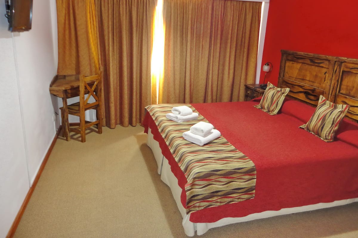 A hotel room with a bed, a desk, and a chair.