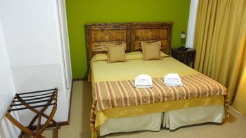 Una habitación de hotel con una cama grande, un cabecero de madera, una mesita pequeña y una silla.