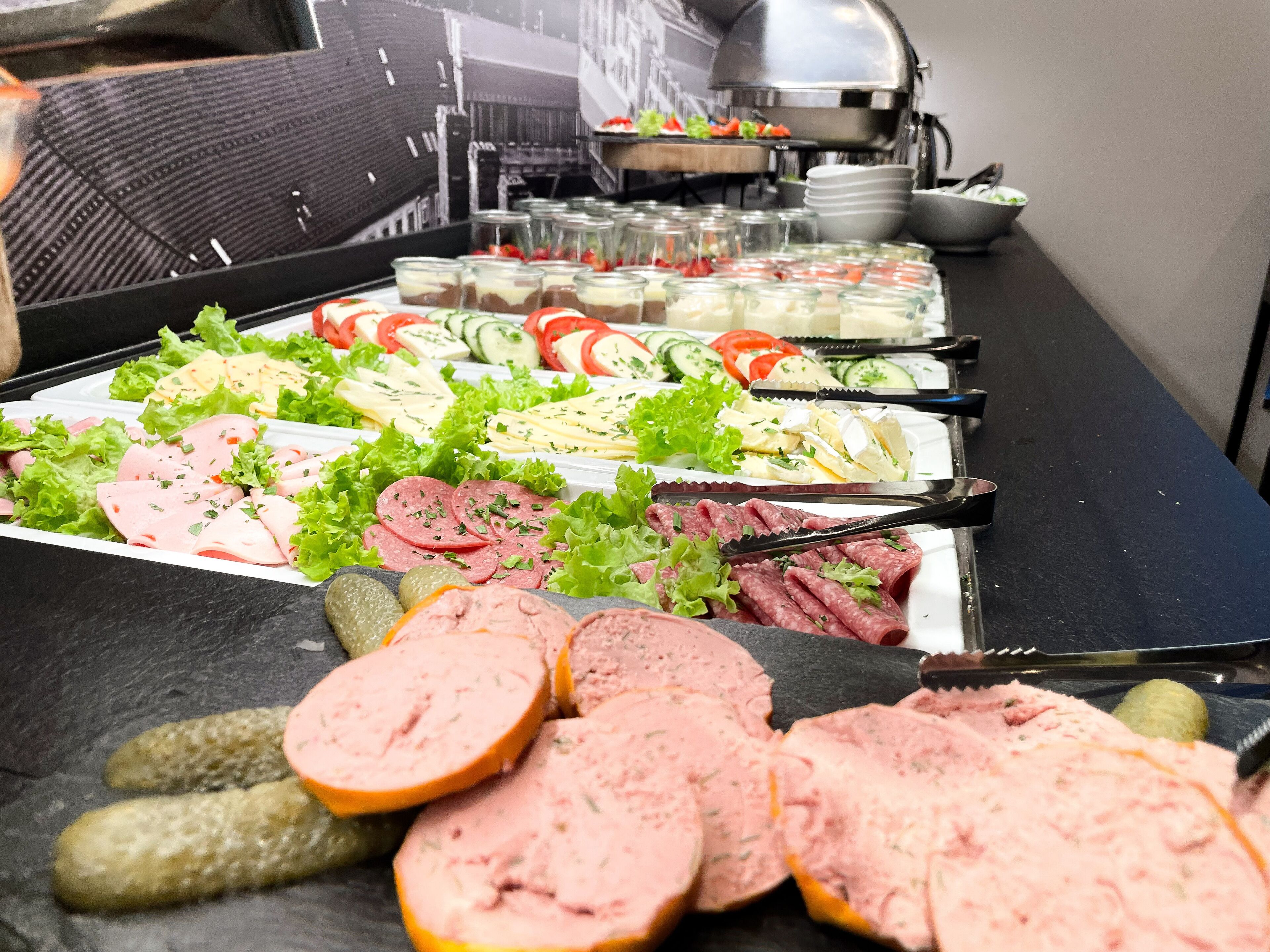 A buffet with various food items including meats, cheeses, and salads.