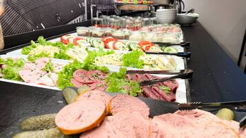 A buffet with various food items including meats, cheeses, and salads.