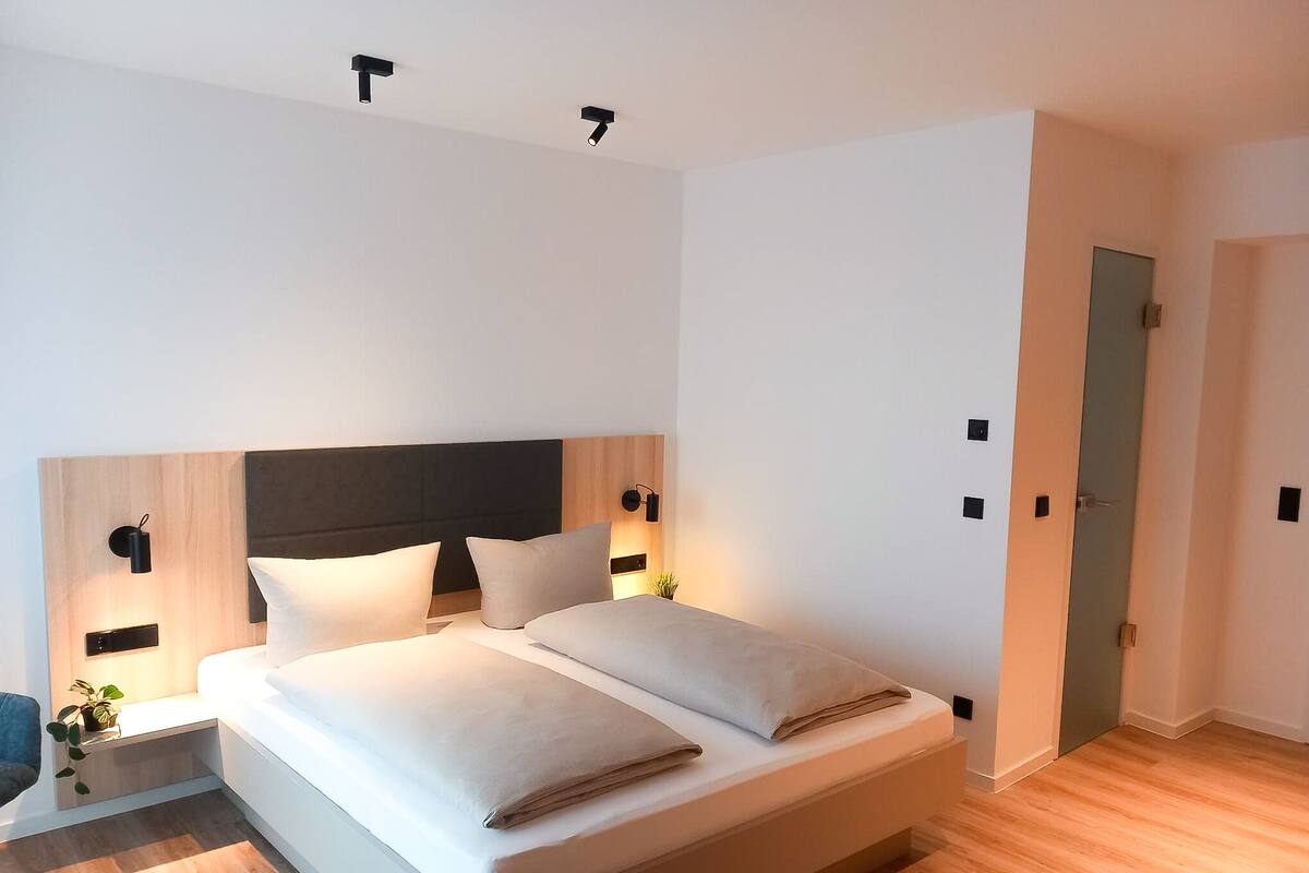 A modern bedroom with a large bed, bedside tables, and a nightstand.