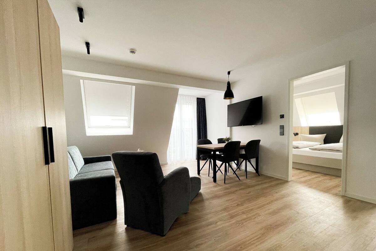 A modern, open-plan living space with a dining area, a sofa, and a bed.