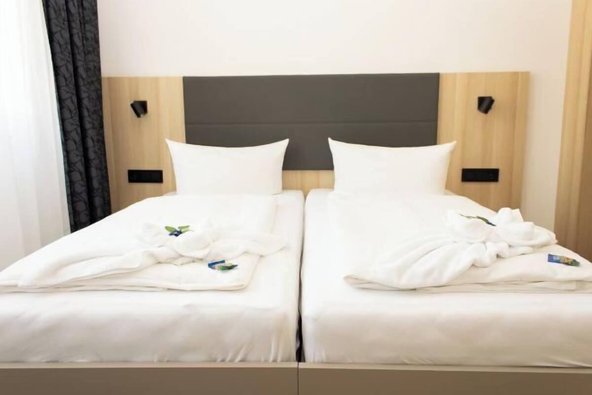 A double bed with a wooden headboard, white bedding, and two bedside tables with black lamps.