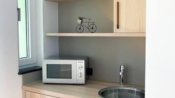 Una cocina compacta con microondas, pileta y muebles de madera.